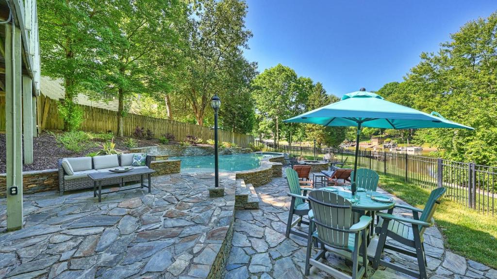 Un patio con una mesa y sillas y una sombrilla. en Sun Up Sun Down by AvantStay Pool w Waterfall, en Mooresville