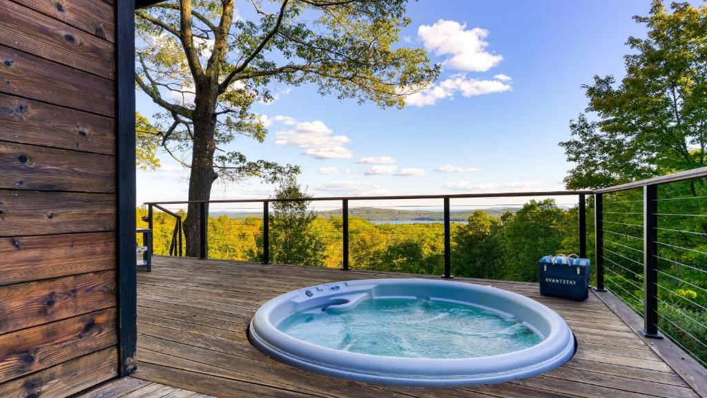 Una bañera de hidromasaje en una terraza con vistas. en Modern Catskills Escape w Open Living Steam Shower Hot Tub w Mountain Views Minutes from Woodstock Trails Suncliff Vista, en Shokan