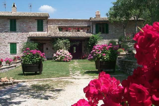 una casa con flores rosas delante de ella en L'Oasi en Piano Delle Pieve