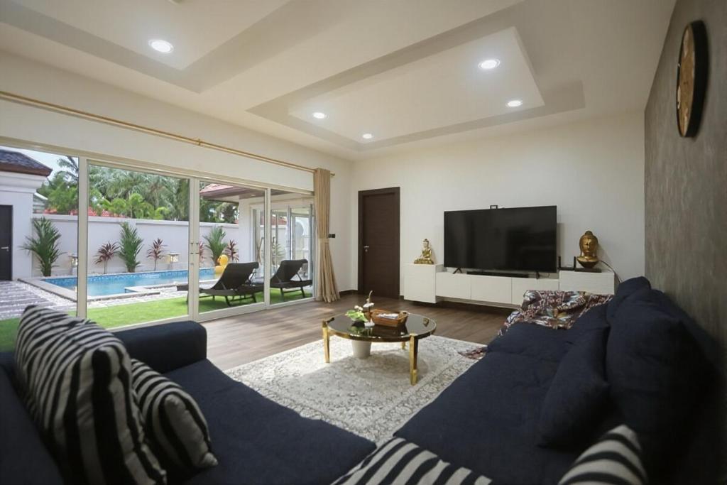 a living room with a blue couch and a tv at Pattaya View Talay Villa-Family Luxury Private Pool Villa,2BR, Walk to Beach in Jomtien Beach