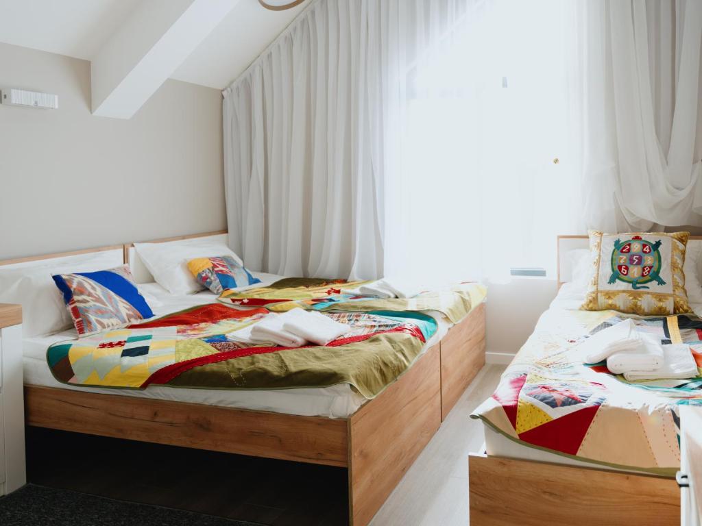 two twin beds in a bedroom with white walls at Skeramos Boutique Art Hotel in Bishkek