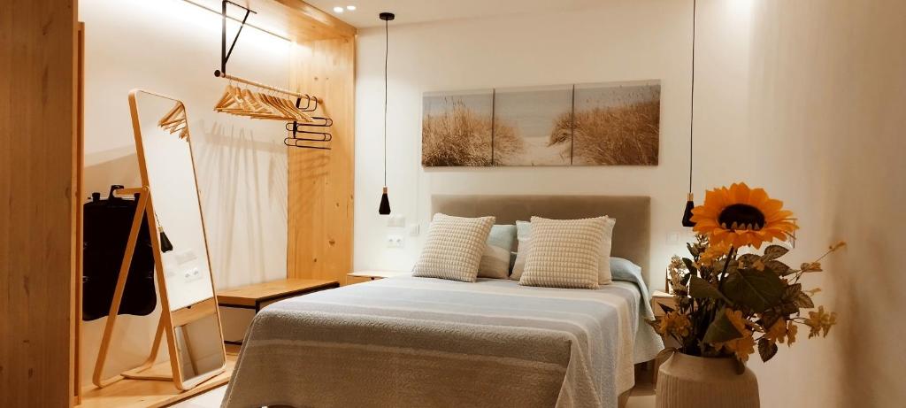a bedroom with a bed and a vase with a sunflower at Estudio centro de La Laguna in La Laguna