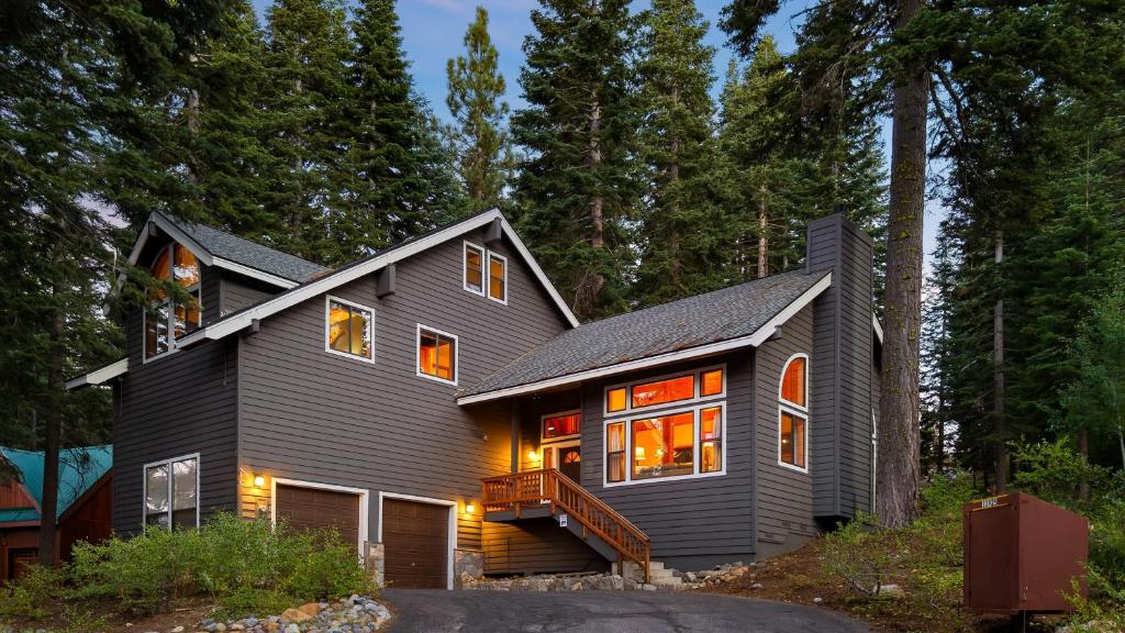 a black house with lights on in the forest at Cozy Escape w Hot Tub Deck & Access to Tahoe Donner & Skiing Alpenglow Chalet by AvantStay in Truckee