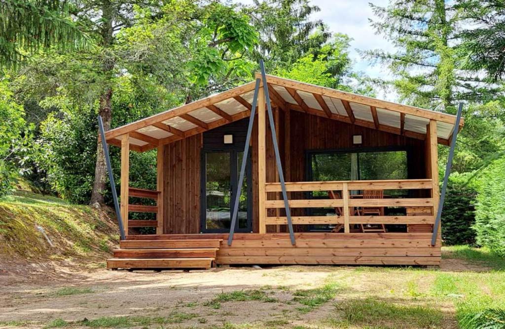 eine kleine Holzhütte mit einer Veranda auf einem Feld in der Unterkunft Camping les Pialades -Chalet Mimosa in La Mouline