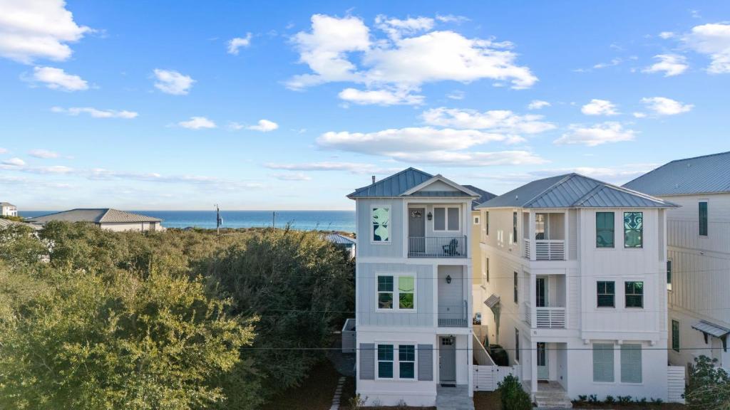 a white house with the ocean in the background at The Palmetto Blue by AvantStay Steps to Beach Ocean Views in Inlet Beach
