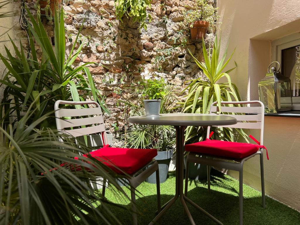 two chairs and a table in a room with plants at Les Petits Volets Appartements à 100m de la mer in Antibes