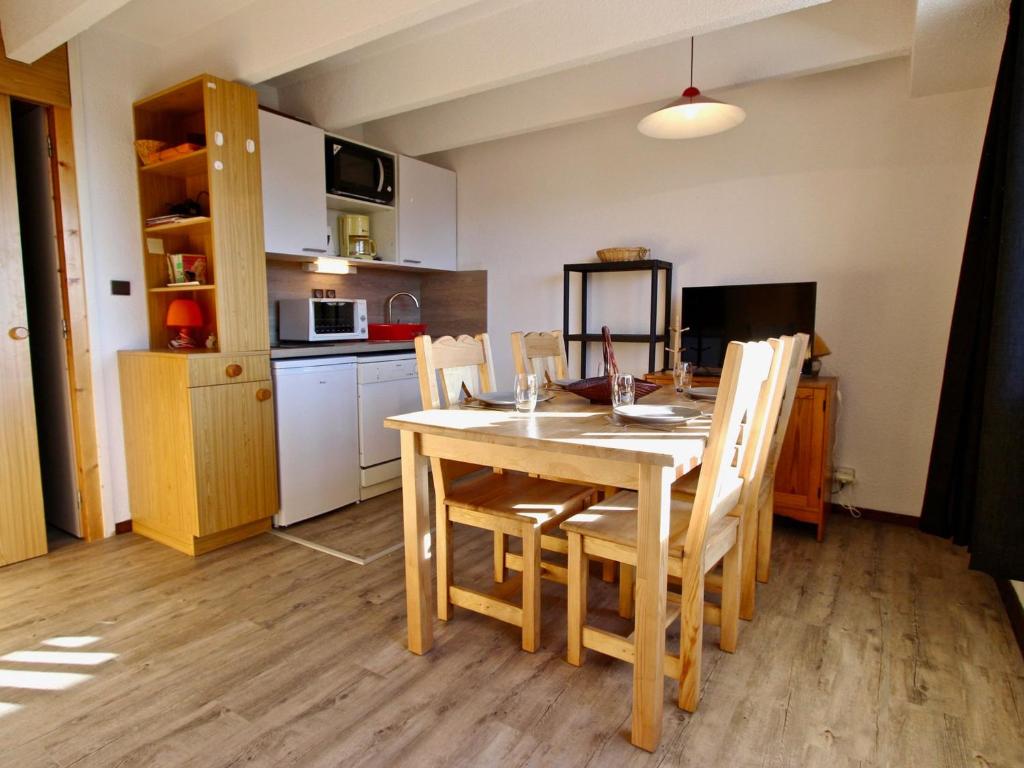 una cucina con tavolo da pranzo e sedie in legno di Studio cabine avec parking couvert à Chamrousse - FR-1-340-122 a Chamrousse