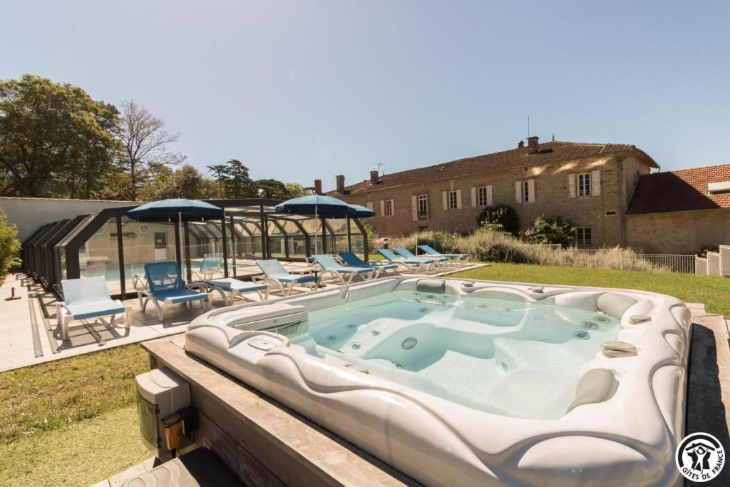a hot tub on a deck with chairs and umbrellas at Chambres d'hôtes de montcausson in Revel