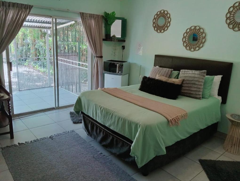 a bedroom with a large bed and a balcony at Be Our Guest Near OR Tambo International Airport 2 in Boksburg