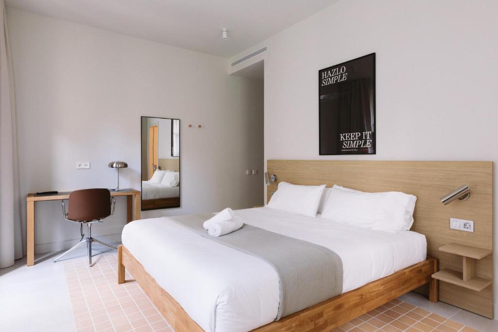 a bedroom with a large white bed and a desk at Outsite Barcelona in Barcelona