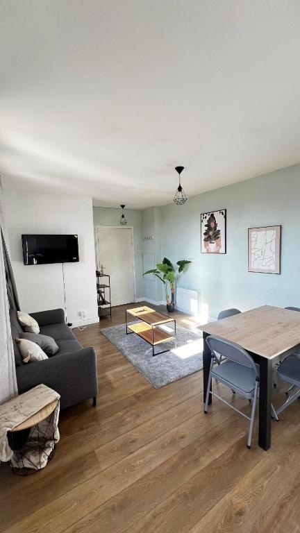 a living room with a couch and a table at Superbe appartement en Hauteur style NEW Yorkais - Proche Métro Paris Idéal pour couple et professionnels Toutes commodités à proximité in Saint-Ouen