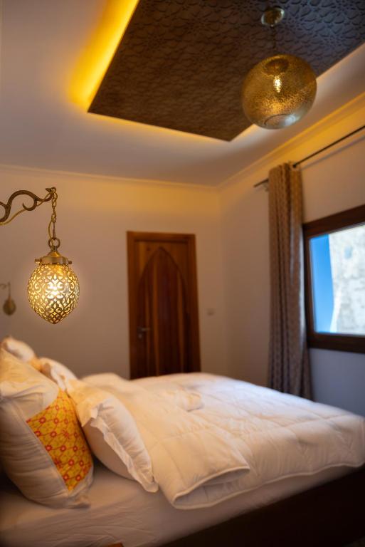 a bedroom with a bed with white sheets and a window at Diyar Marhaba in Chefchaouen