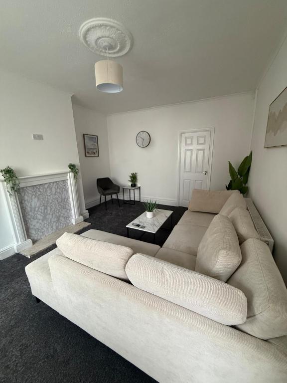 a white living room with a large white couch at ResiLets Taylor House in Bebside