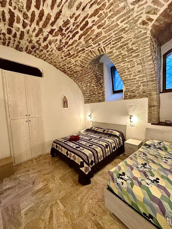 a bedroom with two beds and a stone wall at Casa Vacanza DEL PONTE in Gubbio