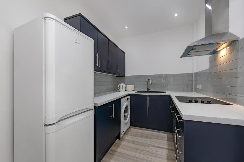 滨海克拉克顿The Pier Escape Sea Breaze Stay的厨房配有蓝色橱柜和白色冰箱