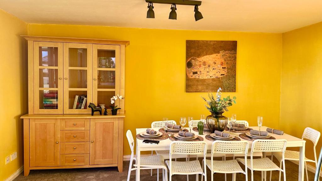 a dining room with a table and white chairs at Sunny day new flat with 5 beds in Clydebank