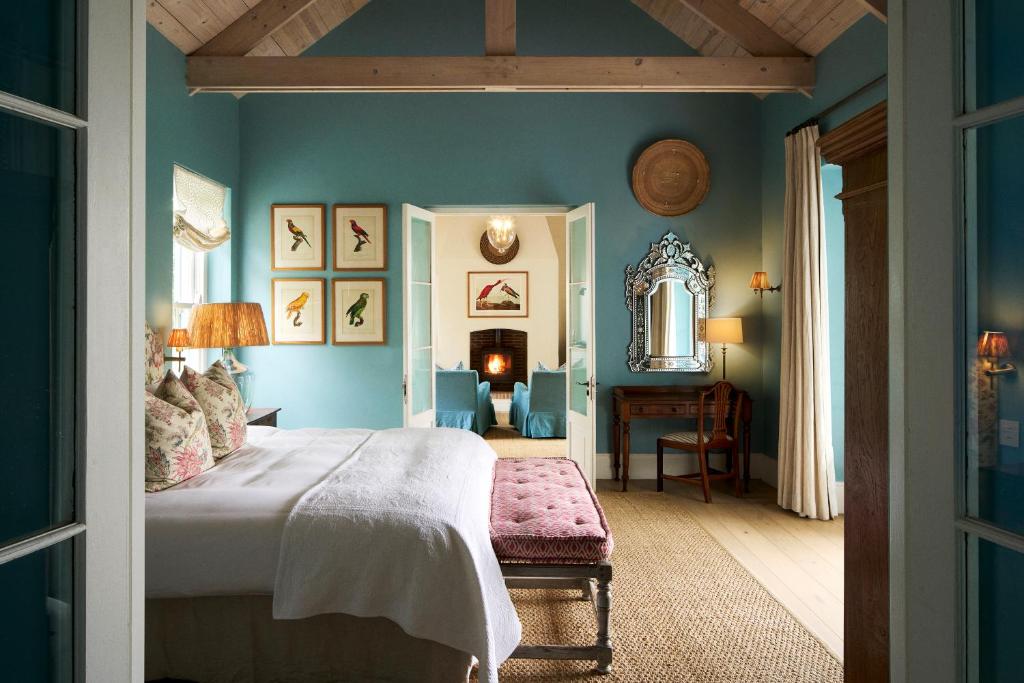 a bedroom with blue walls and a large bed at La Cotte Orchard Cottages in Franschhoek