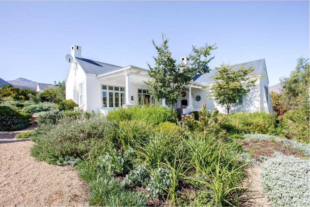 a white house with plants in front of it at La Cotte Orchard Cottages in Franschhoek