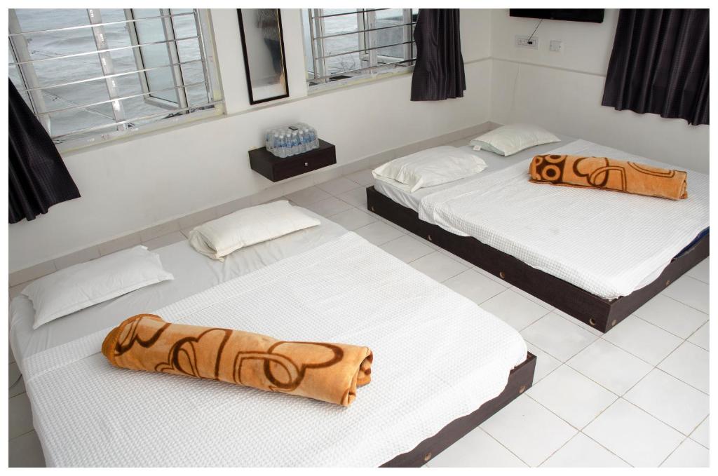 - 2 lits dans une chambre dotée de parquet blanc et de fenêtres dans l'établissement Mubeen beach villa, à Pondichéry