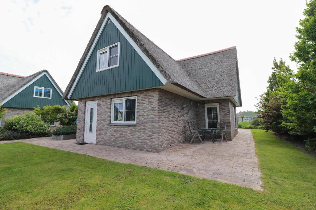 ein Haus mit einem grünen Dach und einem Hof in der Unterkunft Beachvilla - 5 personen in Holle Poarte