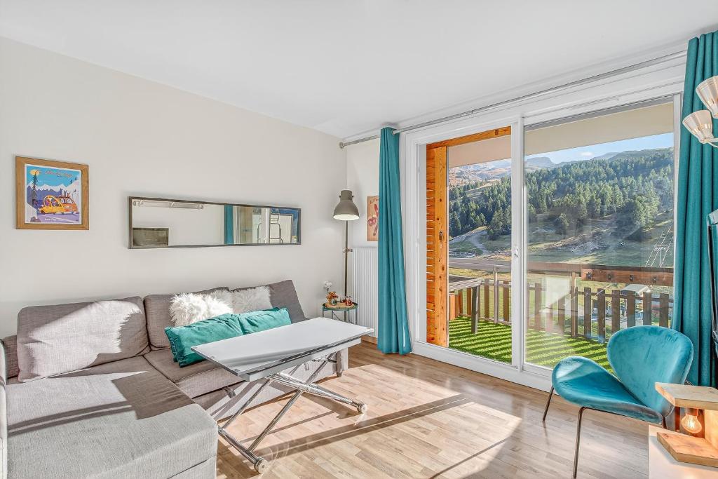Una sala de estar con un sofá y una ventana grande. en Appartement Tout Confort, en Superdevoluy