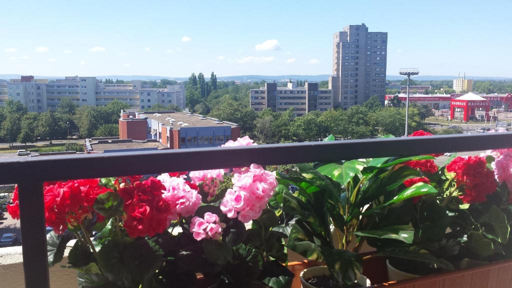 uma varanda com flores cor-de-rosa e vista para a cidade em LANE City Laatzen em Hanôver