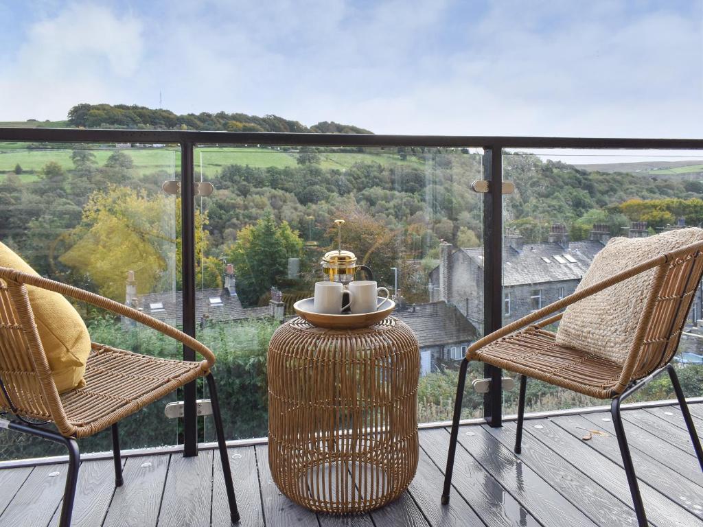 a balcony with two chairs and a table with a view at Seamstress Cottage in Ripponden