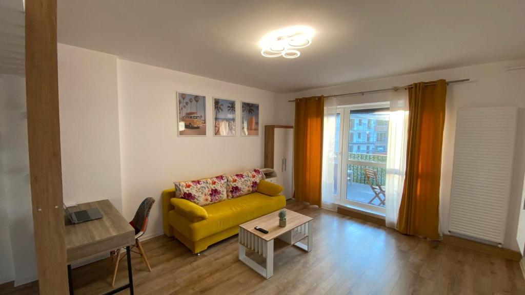 a living room with a yellow couch and a table at LCB Studio Braşov in Braşov