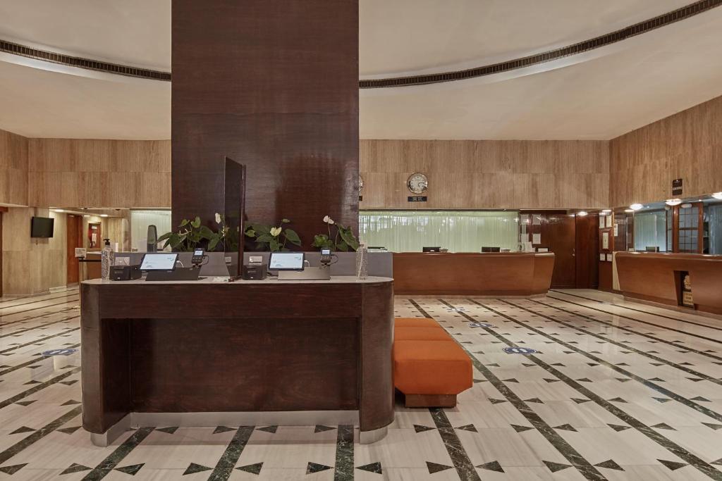 A spacious reception lobby uses dark wood desks, marble-patterned flooring and warm wood wall finishes.