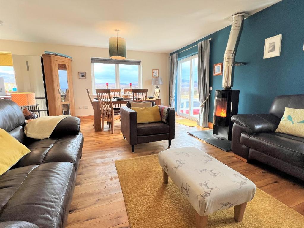 a living room with leather furniture and a fireplace at Hirta Cottage in Staffin