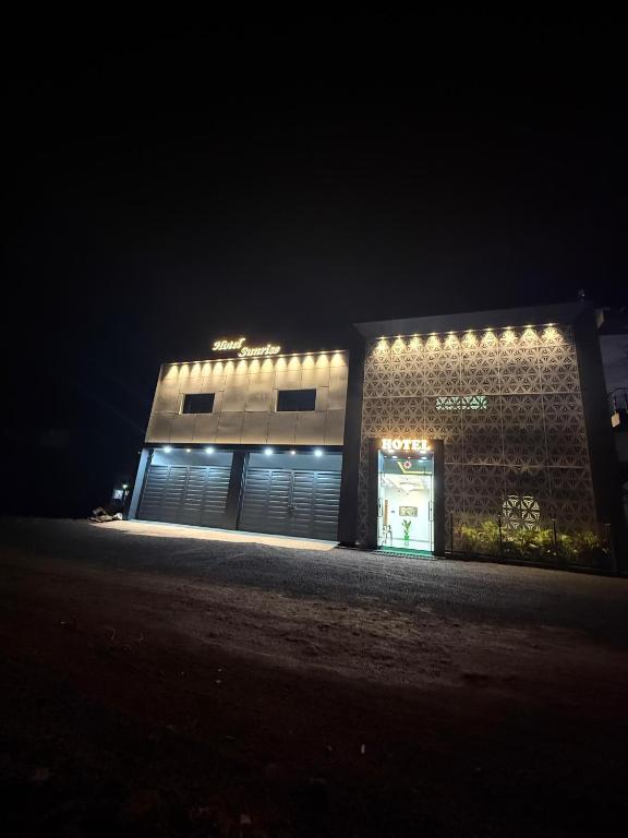 a building with lights on the side of it at night at Hotel Sunrise in Ādkot