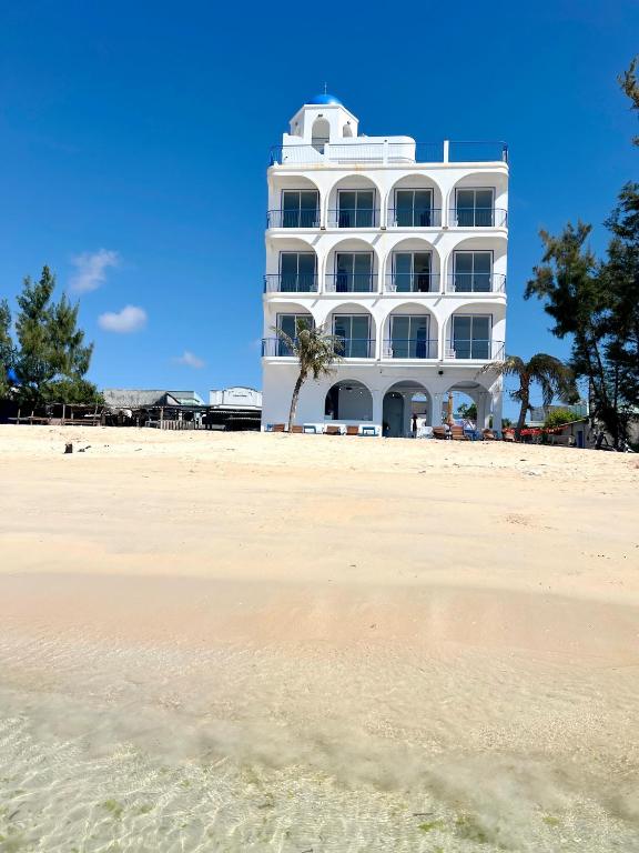 a white building on the beach next to a sandy beach at Babylon Hotel Phu Quy in Cu Lao Thu