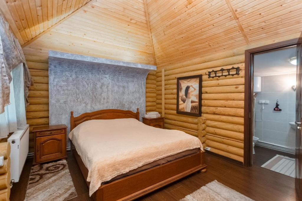 a bedroom with a bed in a room with wooden walls at Poiana Bradului Complex Hotelier & Restaurant in Chişinău