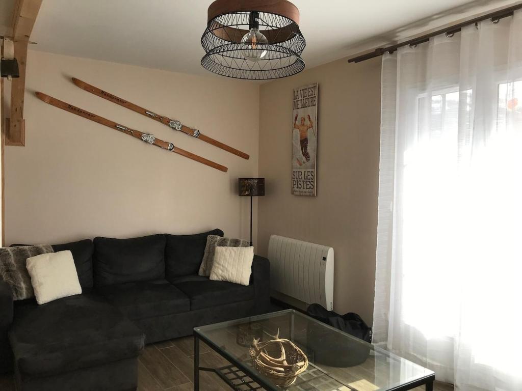 a living room with a black couch and a glass table at Maison "L' Ostal De Montanha" in Génos