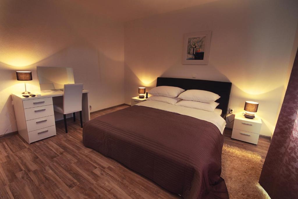 ein Schlafzimmer mit einem Bett und einem Schreibtisch mit zwei Lampen in der Unterkunft Countryside Apartment in Rakovica