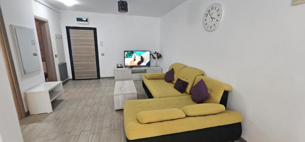 sala de estar con 2 sofás amarillos y TV en ApartHotel Beach & Pool Resort Alezzi langa mare, en Mamaia Nord – Năvodari