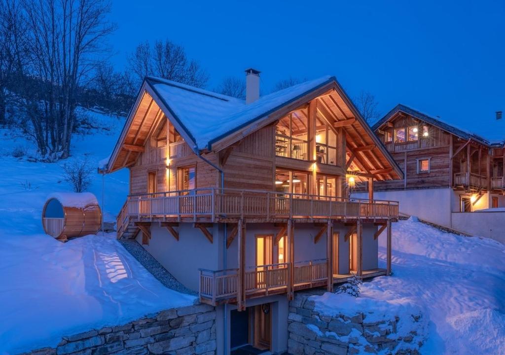 una casa de madera en la nieve por la noche en Chalet Le Refuge Luxe Authenticité Serre Chevalier, en La Salle-les-Alpes