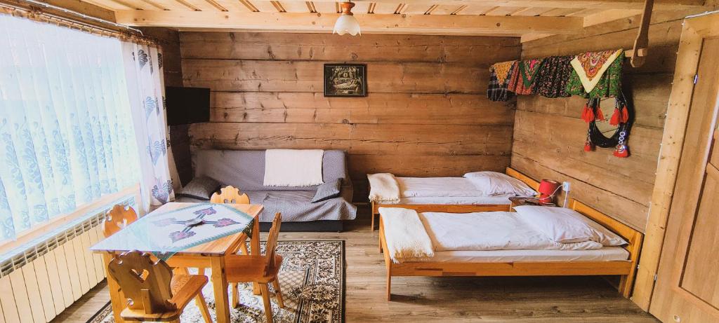 a room with two beds and a table in it at Pokoje Pod Cyrlicą u Józi in Chochołów