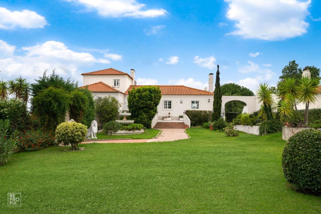 ein großes weißes Haus mit einem grünen Hof in der Unterkunft Villa Casa Beatriz in Palmela in Palmela
