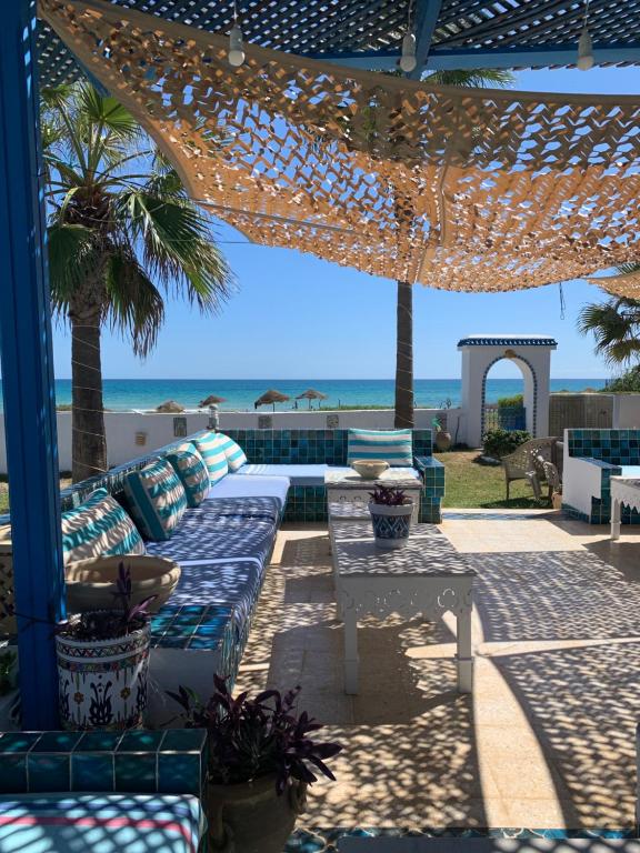 a patio with a couch and a table and the beach at Villa Acqua en front de mer in Nabeul