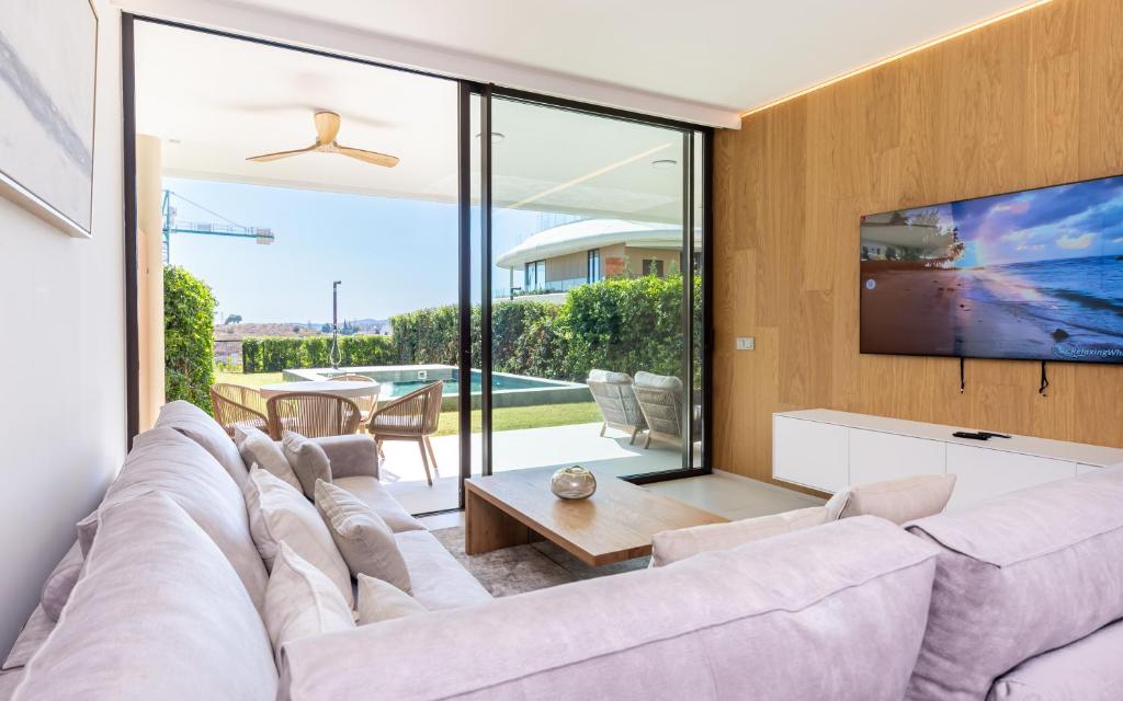 a living room with a large couch and a tv at Eden Retreat Luxury 2BR with Private Pool in Fuengirola
