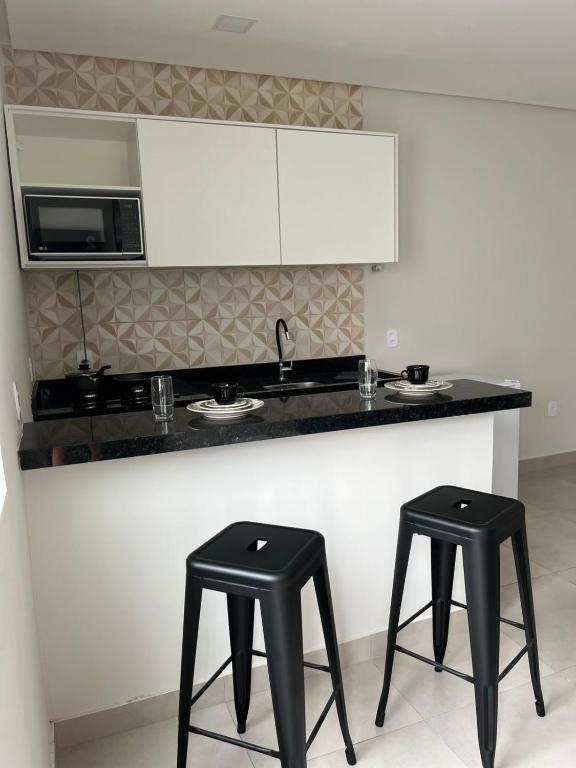 a kitchen with two black stools in front of a counter at CF Flat 03 in Petrolina