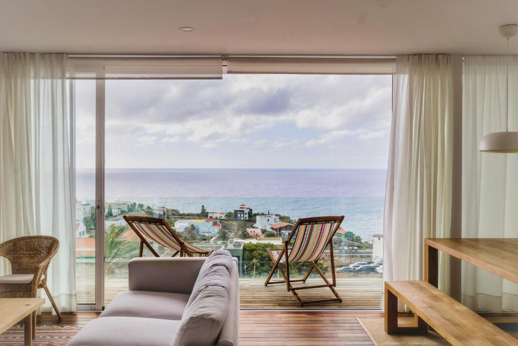 Una sala de estar con un sofá y vista al mar. en Marea Alta, en La Caleta