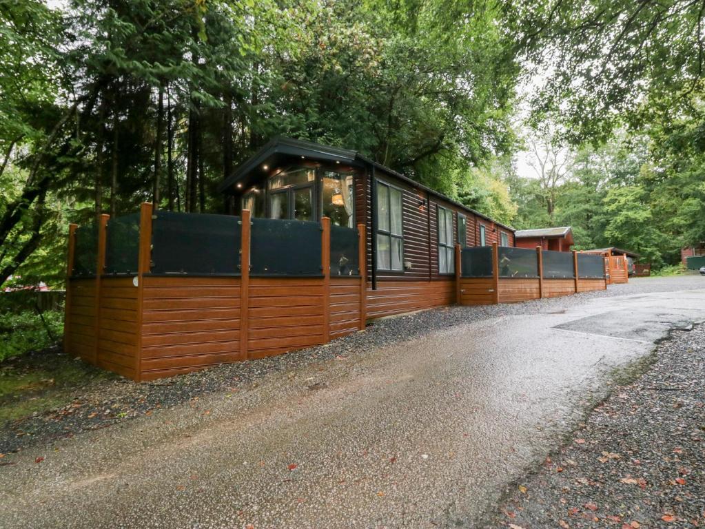 a cabin with a wooden fence on the side of a road at Feather Hill Lodge White Cross Bay, Skiptory Howe 38 in Windermere