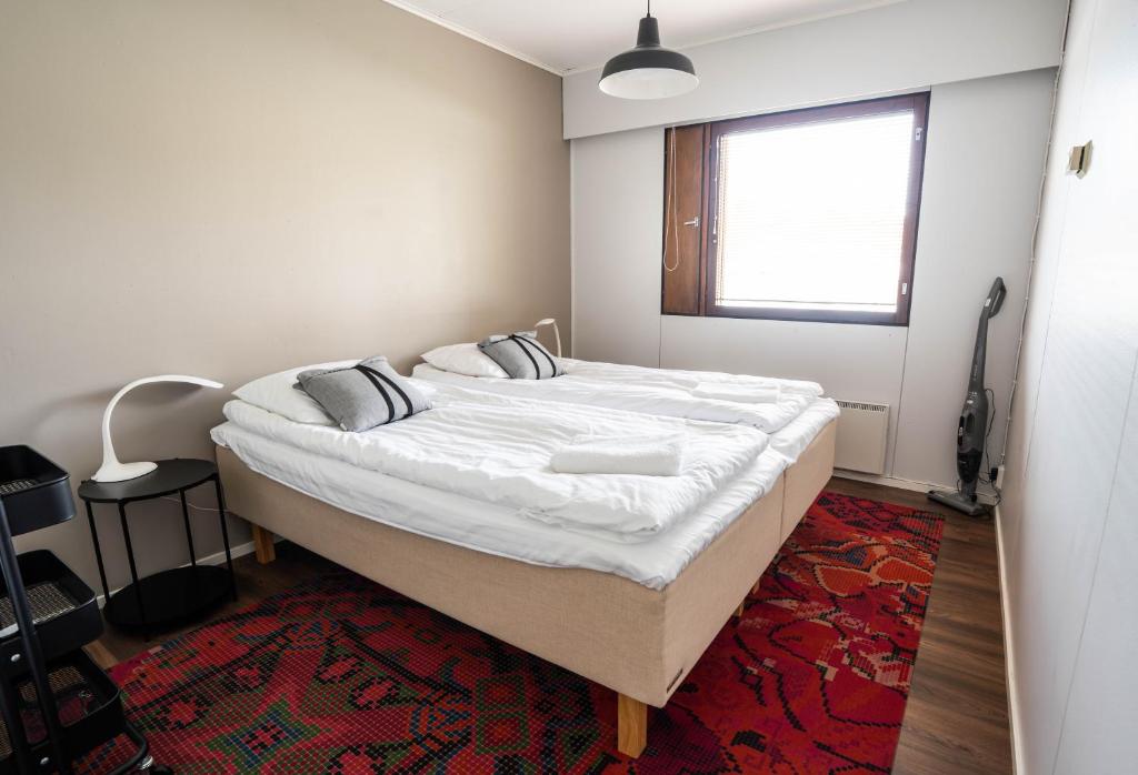 a bedroom with a bed with white sheets and a window at Cozy Ranua Koivutie townhouse with sauna & terrace in Ranua