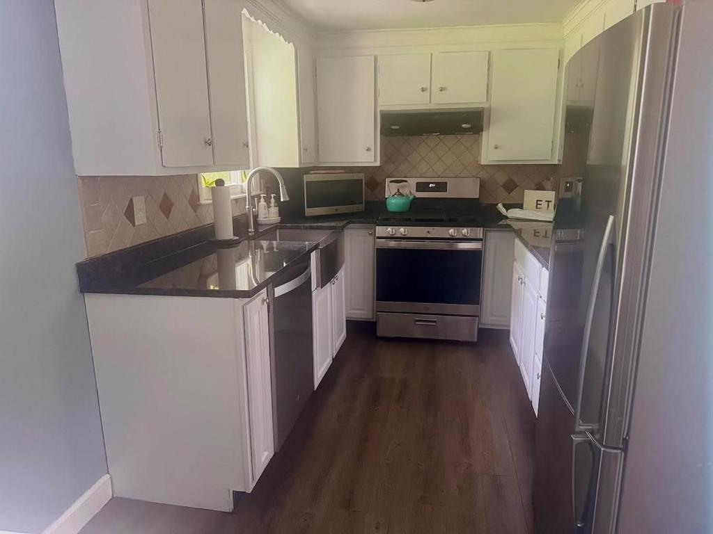 a kitchen with white cabinets and stainless steel appliances at Kamtsur The home in Rawang