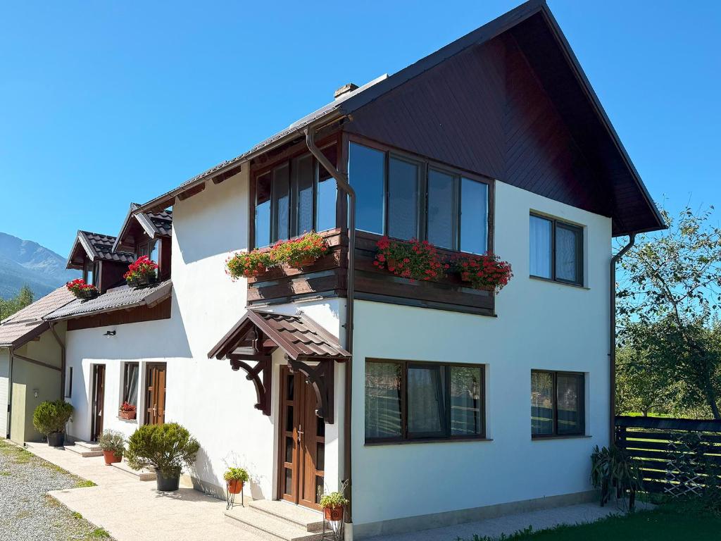 a white house with a black roof and windows at Casuta Fulgu - sa te simti ca acasa! in Borşa