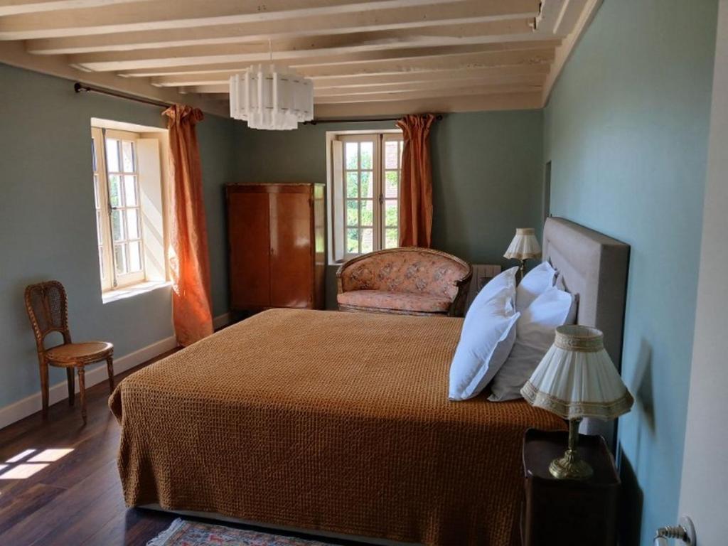 a bedroom with a bed and a chair and windows at D OR et D ARGENT in Arceau