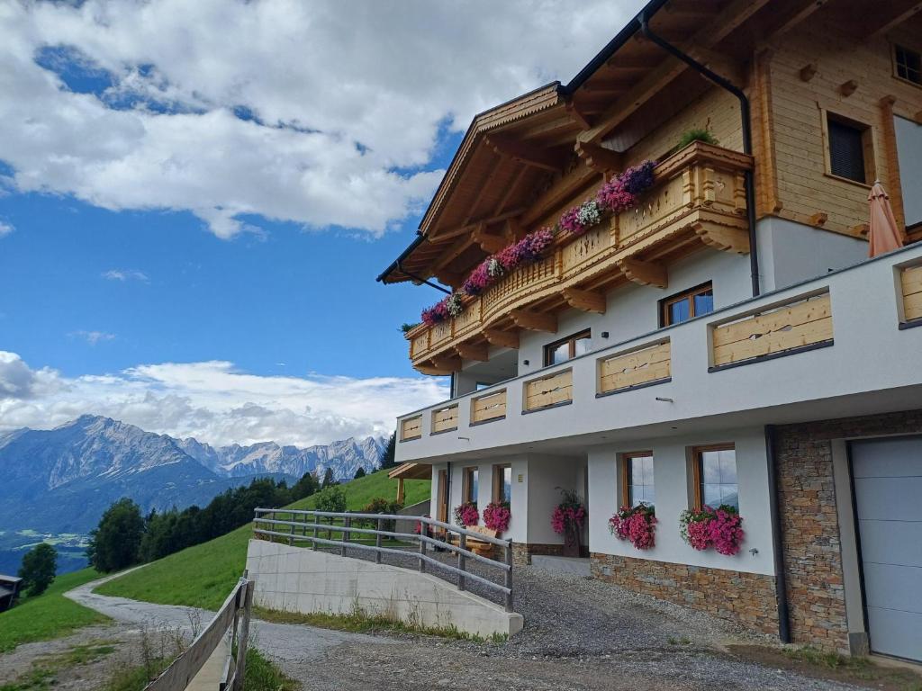 a building on a hill with flowers on the balcony at Ferienwohnung Gipfelblick in Weerberg