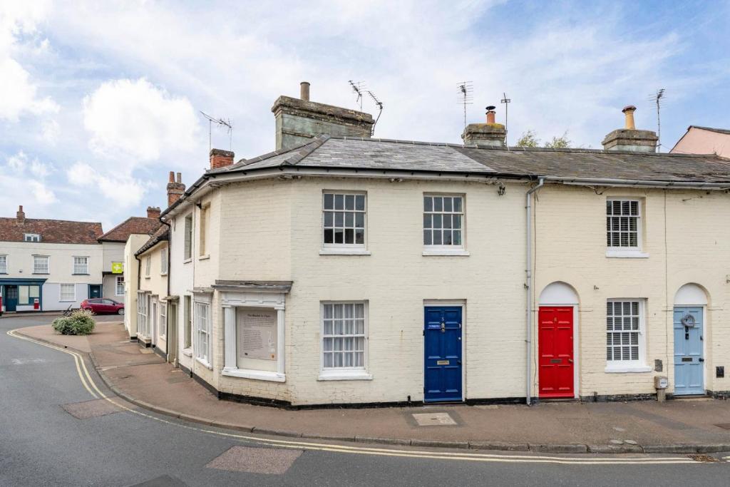 ClareにあるThe Old Shoe Shop, 5 Well Laneの通りに面した赤と青のドアが付いた白い家